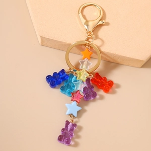 Close-up of colorful resin gummy bears and vibrant star charms on a gold keychain link