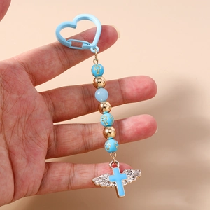 Detail of beaded keychain with cross charms and silver angel wings held in hand