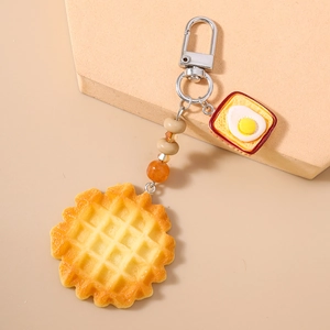 Close-up of realistic waffle and fried egg toast keychain with beaded chain and lobster clasp