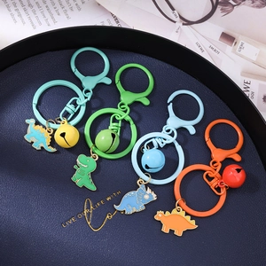 Cartoon dinosaur keychains with colorful enamel charms and bells in four vibrant colors