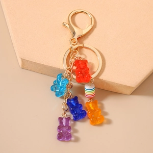 Colorful resin gummy bear keychain with gold clasp and rainbow bead on a minimal background