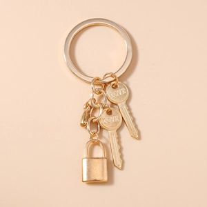 Detail of a golden alloy keychain with LOVE engraved keys and a rectangle padlock charm