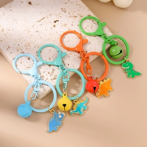 Set of four colorful enamel dinosaur keychains with bells and lobster clasps on beige background