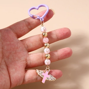 Close-up of beaded keychain with pink cross beads, glass beads and metal wings