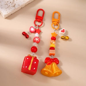 Détail du porte-clés de Noël avec boîte cadeau, cloches et breloques perlées