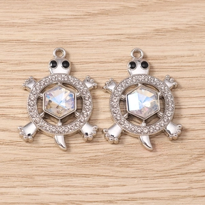 Close-up of silver turtle pendants with rhinestones and iridescent crystals for DIY jewelry