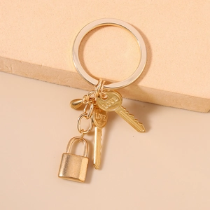 Detail of a gold LOVE lock and key keychain with polished metal charms and droplet pendant