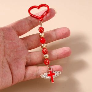 Close-up of gothic beaded keychain with winged red cross pendant and heart-shaped hook