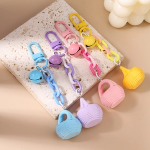 Détail de porte-clés colorés avec panier tressé, clochette et chaîne en plastique épais
