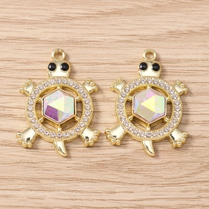 Macro detail of gold turtle charms with AB crystal centers and white zircon stones