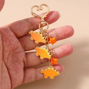 Detail of heart hook keychain featuring orange enamel dinosaurs and stars charms