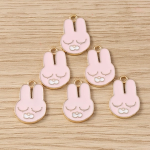 Détail de breloques lapin en émail rose et plaqué or pour la création de bijoux DIY