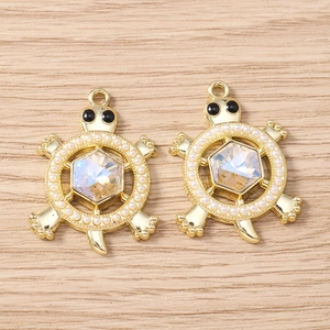 Macro detail of golden sea turtle pendants with rhinestones and faux pearls on wood