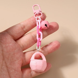 Détail d'une breloque panier tressé rose avec chaîne en plastique et clochette assortie