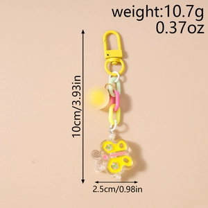 Détail d'un porte-clés papillon coloré avec chaîne épaisse et pendentif sphérique jaune