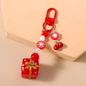 Détail du porte-clés de Noël rouge avec breloque boîte cadeau, cloche et perles