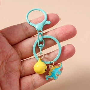 Close-up of cute teal enamel dinosaur keychain with yellow bell and metal hook
