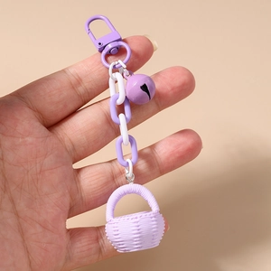 Détail d'un charme panier tressé violet avec chaîne et clochette sur mousqueton