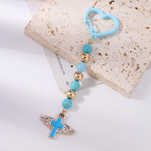 Detail of light blue beaded keychain with winged cross pendant and gold accents