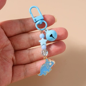 Close-up of a blue dinosaur keychain with metallic bell and star beads for bags