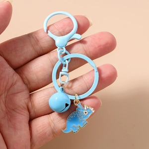 Detailed close-up of a blue enamel dinosaur keychain with metal bell and lobster clasp