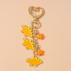 Detail of yellow dinosaur charms and orange star pendants on a golden heart keychain