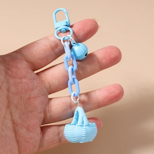 Détail d'un mini panier bleu clair avec chaîne et clochette sur un porte-clés en métal