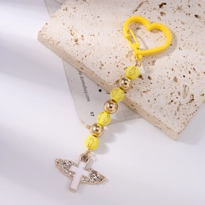 Detail of beaded keychain with heart carabiner and winged cross pendant in gold and yellow