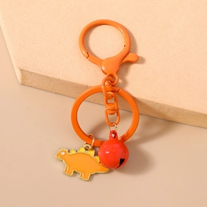 Close-up of orange dinosaur keychain with bell and spring hook on stone display