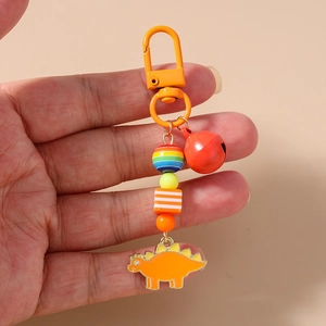 Detail of colorful beaded keychain with orange stegosaurus pendant and bell held in hand