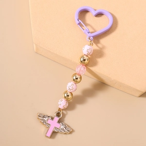 Detail of pink and purple beaded keychain featuring gold wings and a cross pendant