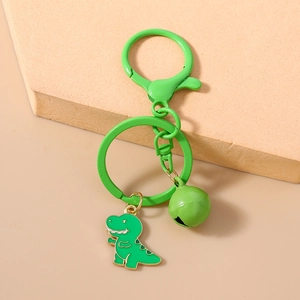 Detailed close-up of a green cartoon dinosaur keychain with a matching bell and lobster clasp