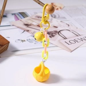 Détail d'un porte-clés panier jaune avec chaîne en plastique et petite clochette en métal