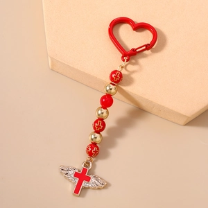 Close-up of red and gold beaded keychain with heart carabiner and angel wing cross