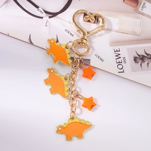 Detail view of cute orange dinosaur charms and star keychain with heart-shaped metal hook
