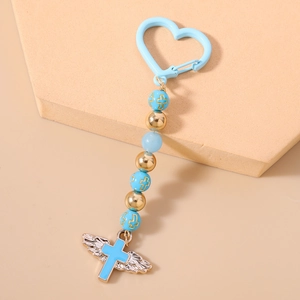 Detail of light blue beaded keychain with golden cross icons and textured silver wings