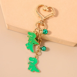 Close-up of green enamel dinosaur charms with gold heart clasp and small round bells