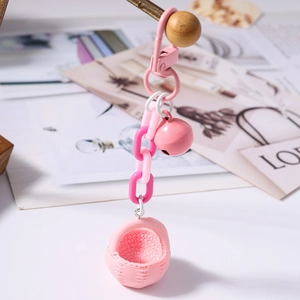 Détail d'un porte-clés à chaîne rose avec une cloche et un pendentif en panier tressé