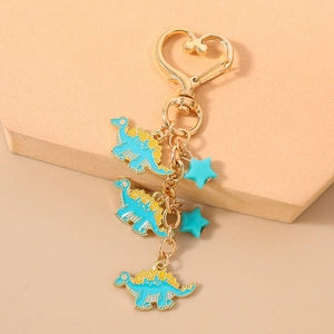 Detail of blue enamel stegosaurus pendants and stars on a gold heart-shaped keychain