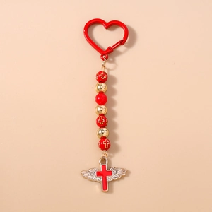 Detail of red beaded keychain with gold cross beads and winged cross pendant charm
