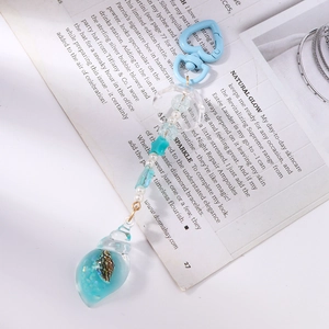 Macro view of ocean style keychain with blue heart clip and transparent resin shell pendant