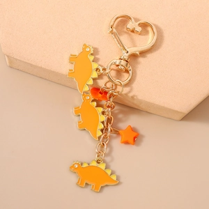 Detail view of heart-shaped clasp and orange dinosaur enamel charms on golden keychain