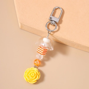 Détail d'un porte-clés avec perles rayées et rose en résine jaune sur un support géométrique