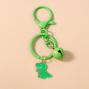 Close-up of a green cartoon dinosaur keychain with matching enamel charm and bell
