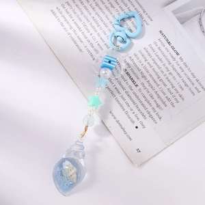 Close-up of ocean-themed beaded keychain featuring a light blue seashell pendant and stars