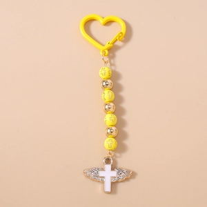 Detailed close-up of yellow beaded keychain featuring cross charms and silver wings
