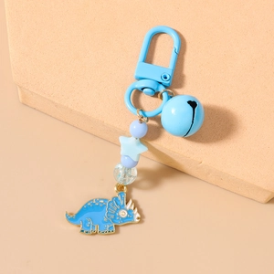 Detail of blue dinosaur keychain with metal bell, star beads, and a triceratops pendant