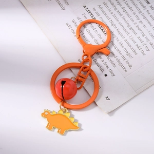 Detail of cute orange dinosaur enamel keychain with matching red bell and metal clasp
