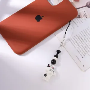 Ziegelrote Handyhülle mit Perlen-Armband und einem weißen Cartoon-Katzenanhänger