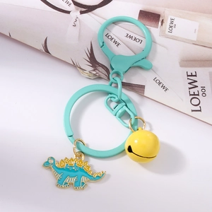 Detail of mint green alloy keychain with a colorful dinosaur charm and a bright yellow bell